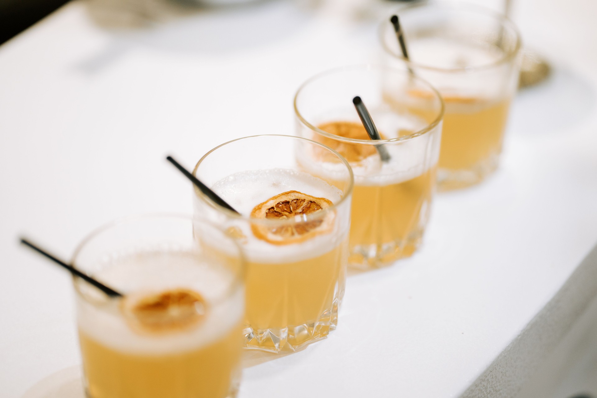 Freshly crafted cocktails lined up on a table at an event during the evening