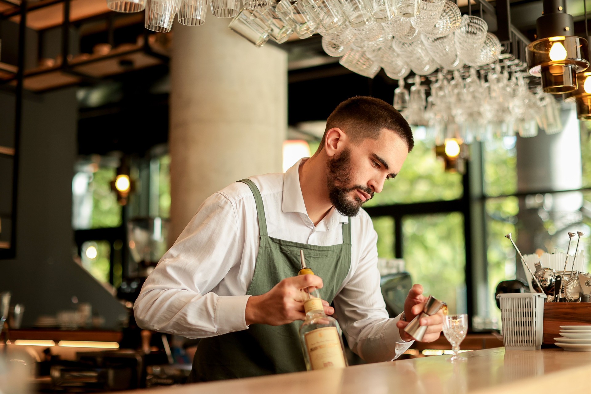Talented bartender skillfully prepares a cocktail at a stylish urban bar on a sunny afternoon, showcasing artistry and precision in mixology
